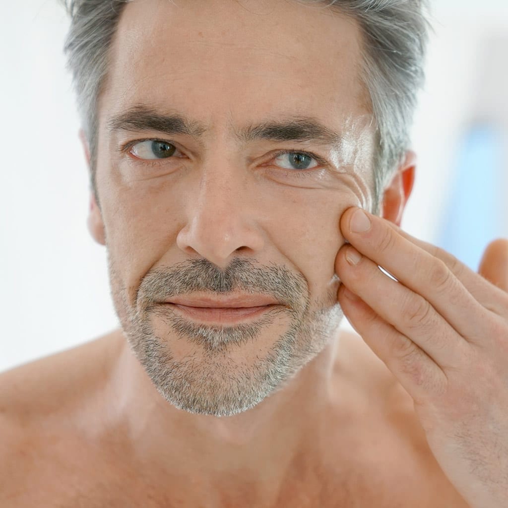 middle aged man examining his face after washing