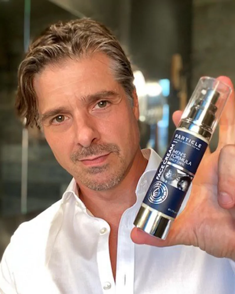 Man showing Particle Men's Formula Face Cream in his hand.
