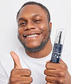 African American man holding Particle Face Cream bottle