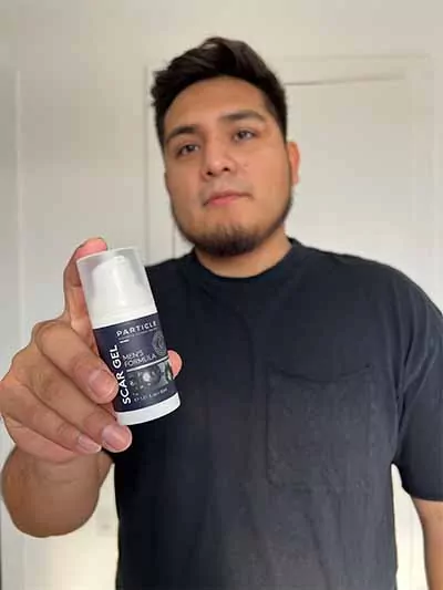 A man showing a Particle Men’s Formula Scar Gel bottle.