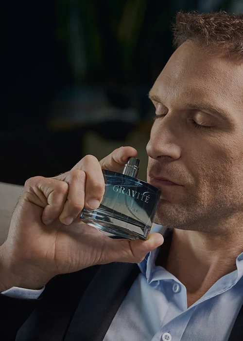 Man smelling Gravité men’s perfume bottle, showcasing a refined masculine fragrance in a close-up lifestyle shot