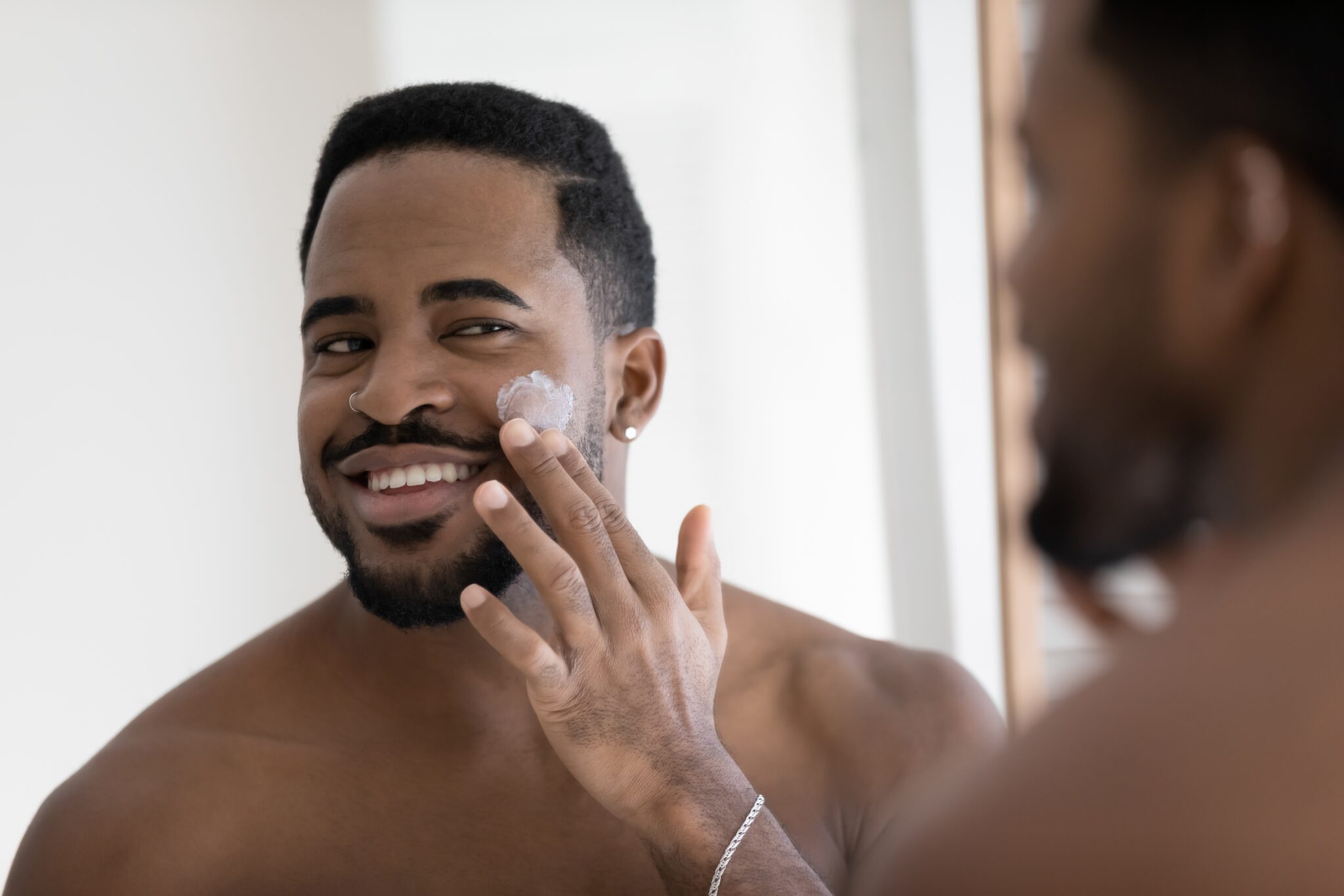 Young,Smiling,African,Man,Reflect,In,Mirror,Apply,Cleanse,Products